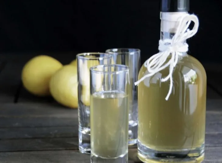 Бутылка хреновухи и рюмки, рядом лимоны