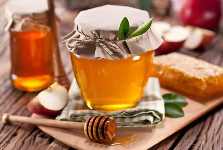 Банки с медом, соты и яблоки на столе