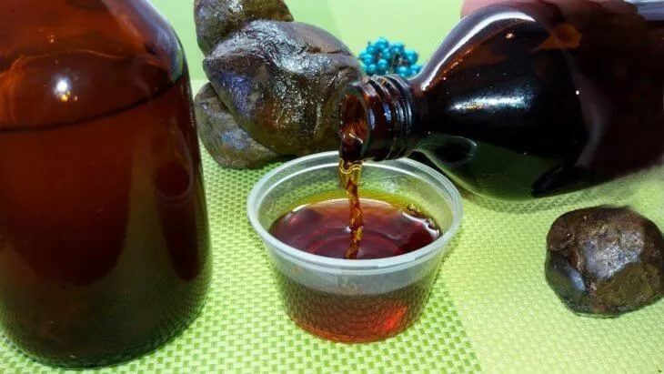 Спиртовая настойка прополиса в стаканчике и кусочки сырого прополиса