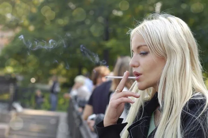 Молодая женщина курит на улице