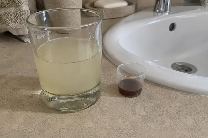 Стакан мутного раствора прополиса и мерный стаканчик с настойкой у раковины