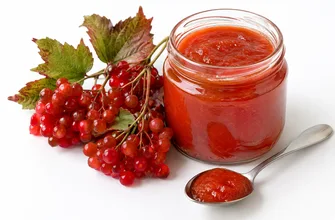 Банка протертой калины с медом, ложка пюре и гроздь красной калины